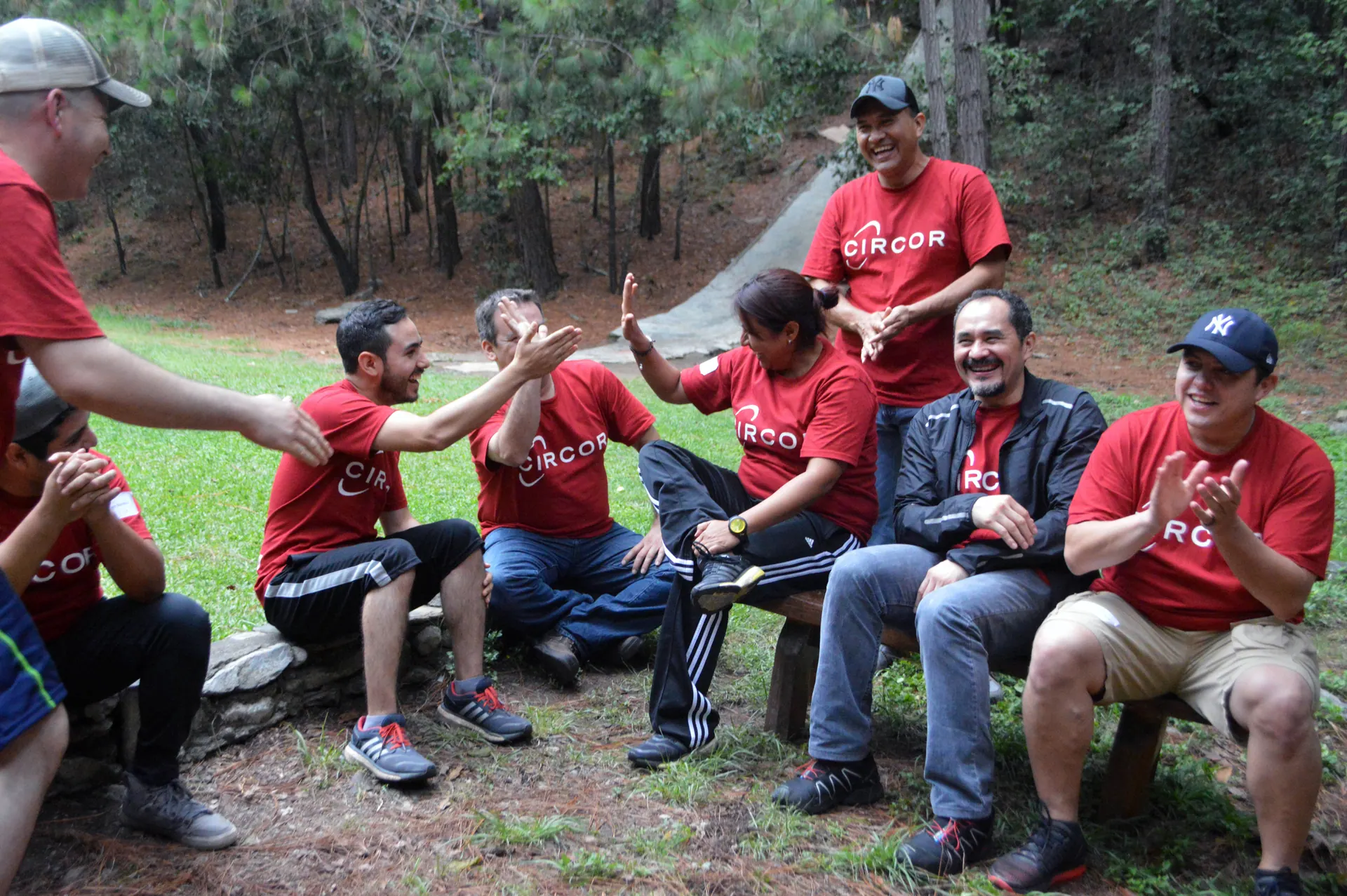 Colaboradores de ALYAX participando en una actividad al aire libre, sentados en troncos, trabajando en equipo en un entorno natural en Monterrey