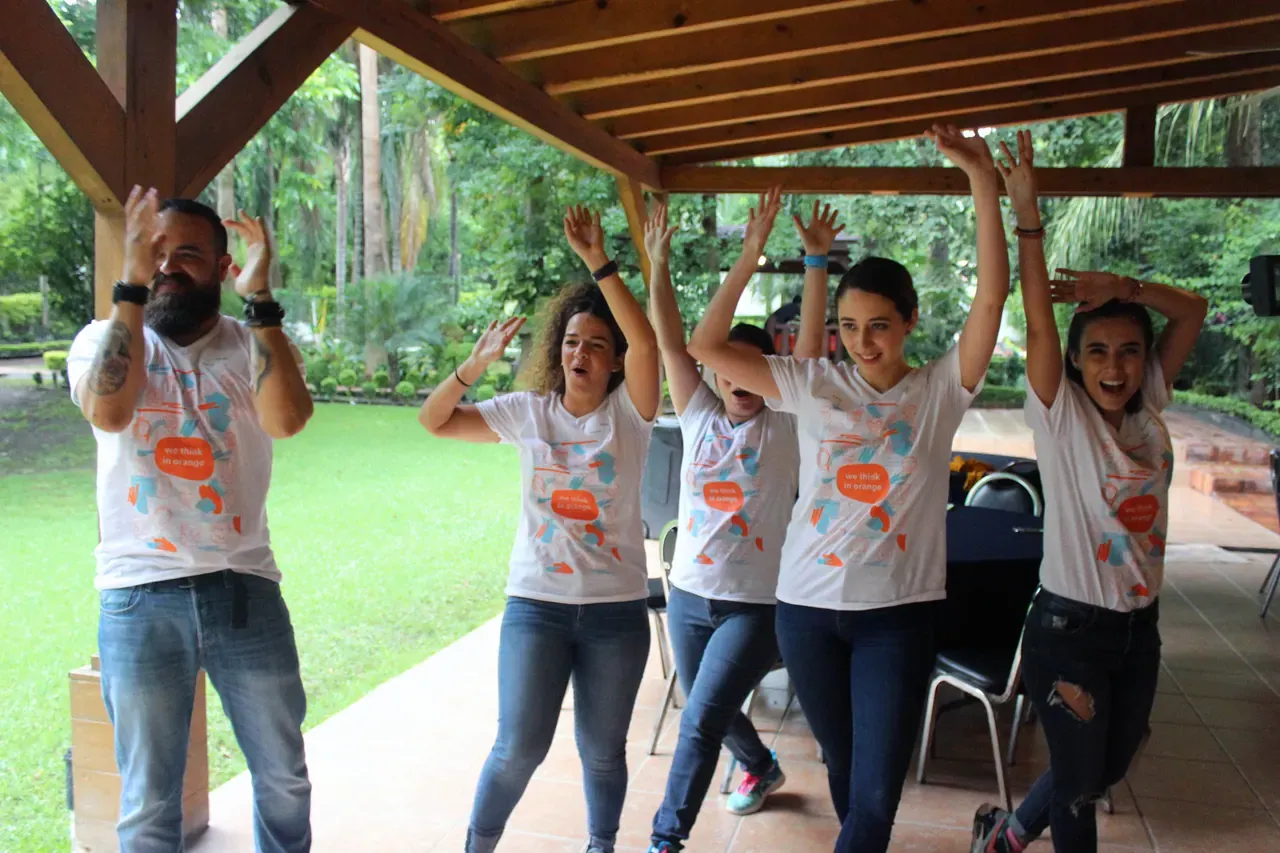 Colaboradores con los brazos en alto durante una dinámica de integración, celebrando como equipo