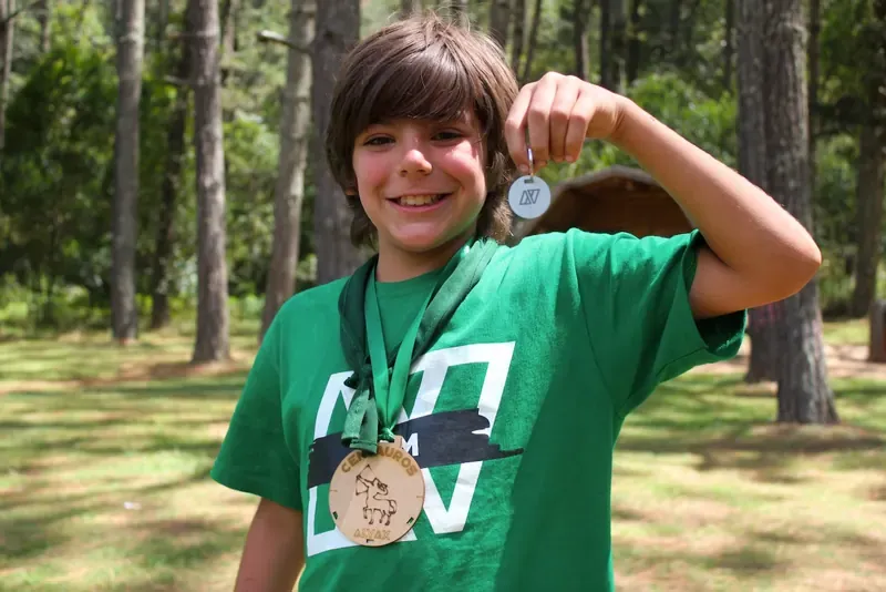 Niño mostrando su medalla del campamento