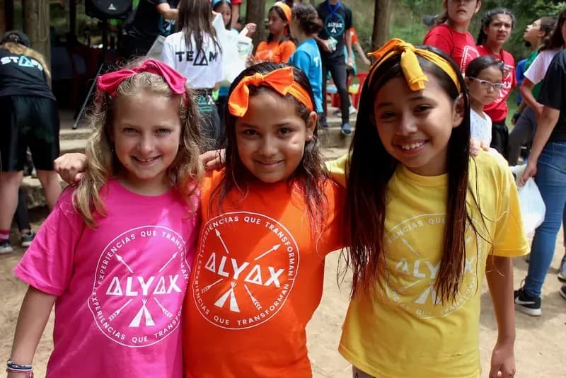 Tres niñas con playeras de colores posando juntas