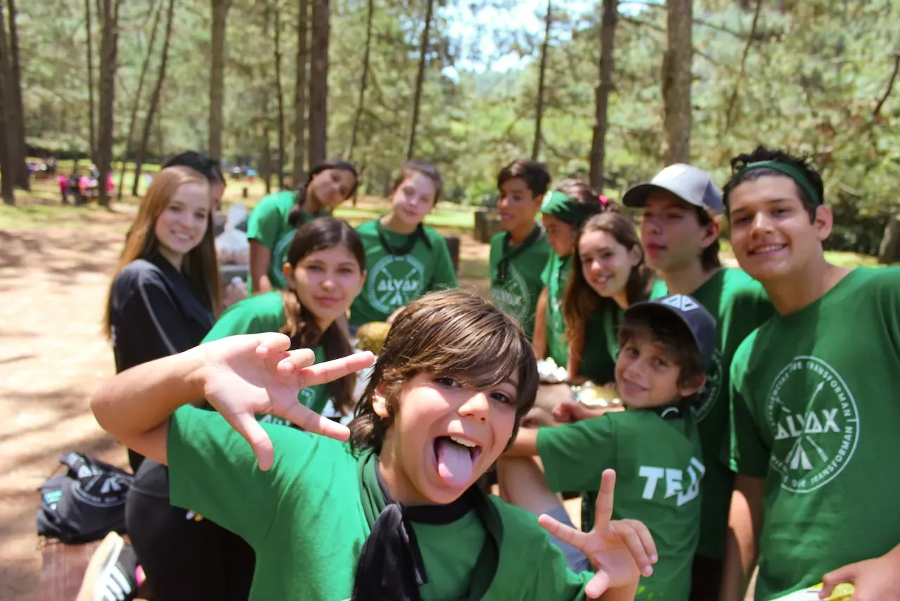Grupo de campistas con playeras verdes haciendo caras divertidas
