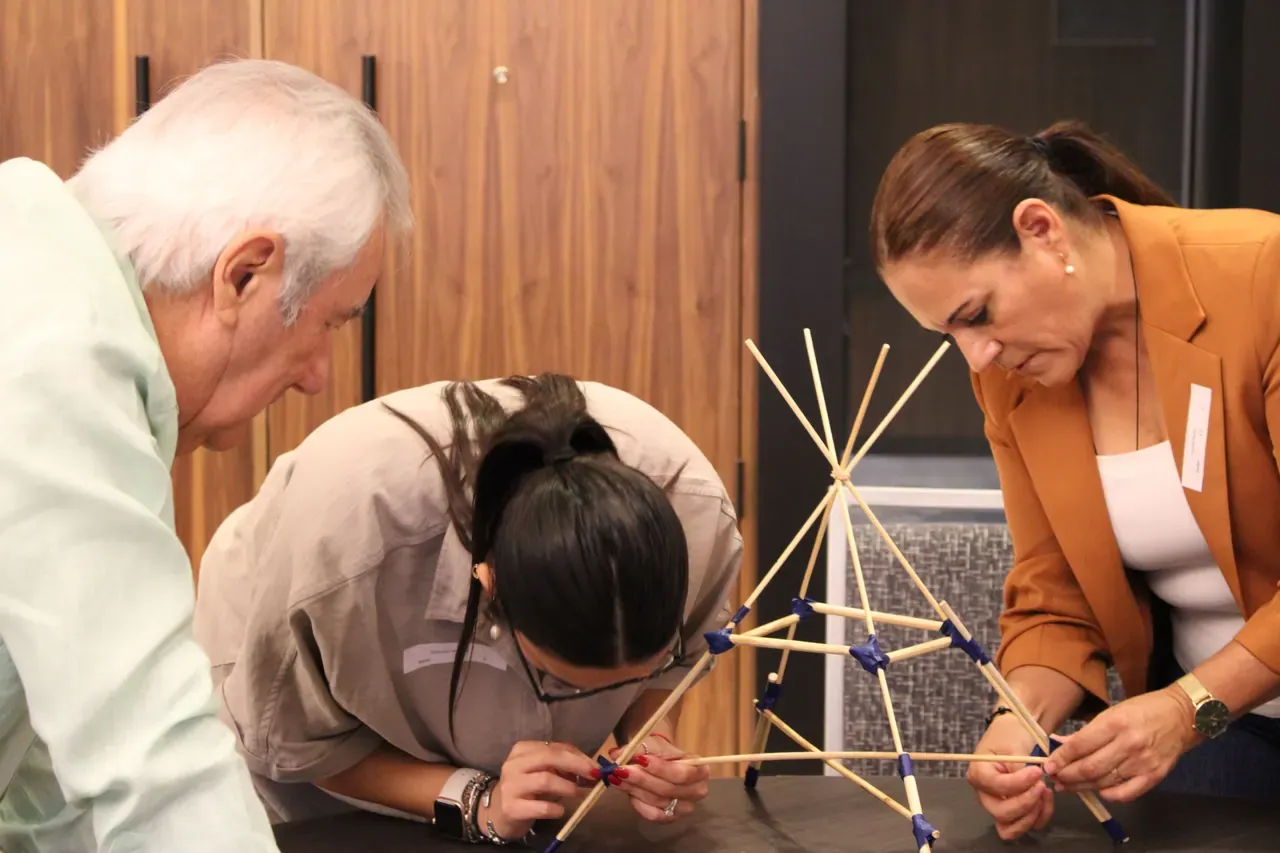 Participantes construyendo una estructura como parte de un ejercicio que fomenta la creatividad y el pensamiento estratégico