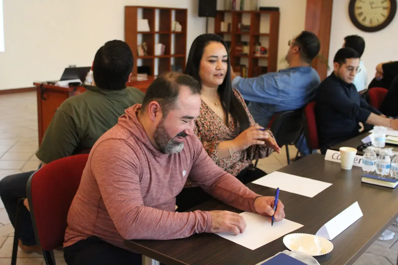 Profesional tomando notas durante una sesión, aprendiendo nuevas estrategias para liderar equipos en entornos competitivos