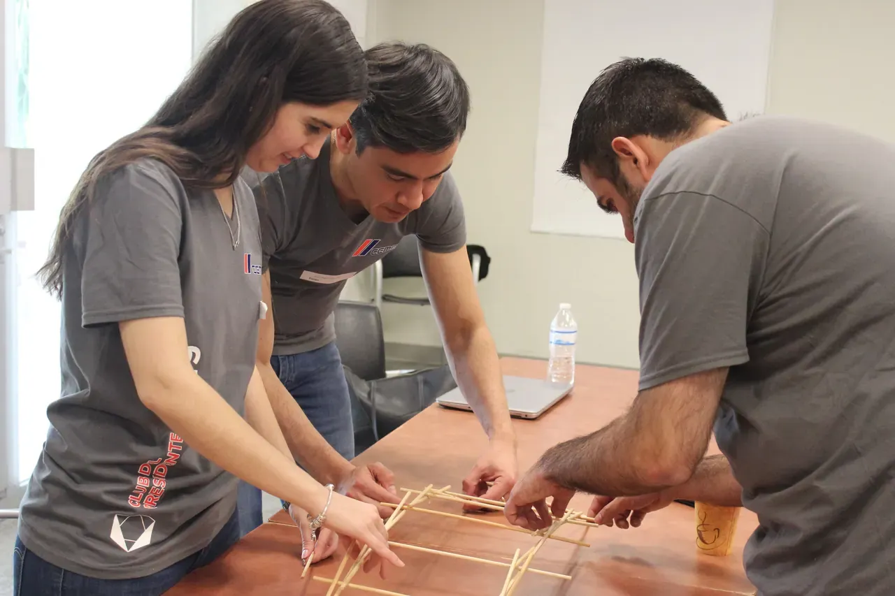 Primer plano de manos ensamblando una estructura de madera, simbolizando creatividad y cooperación en el trabajo en equipo