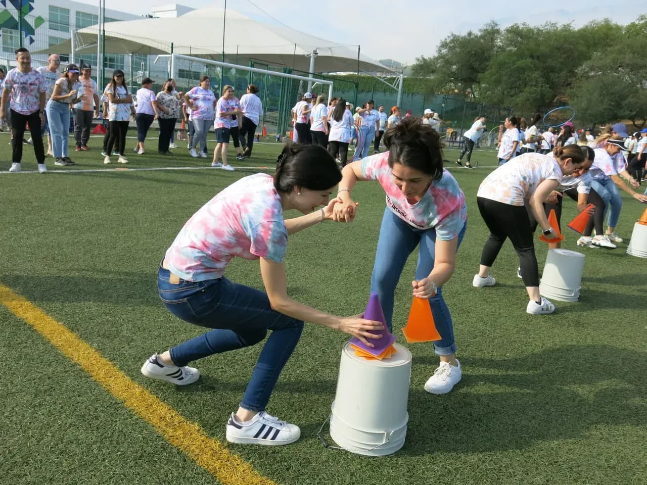 Maestros riendo mientras compiten amistosamente durante una dinámica al aire libre, reforzando la conexión entre colegas