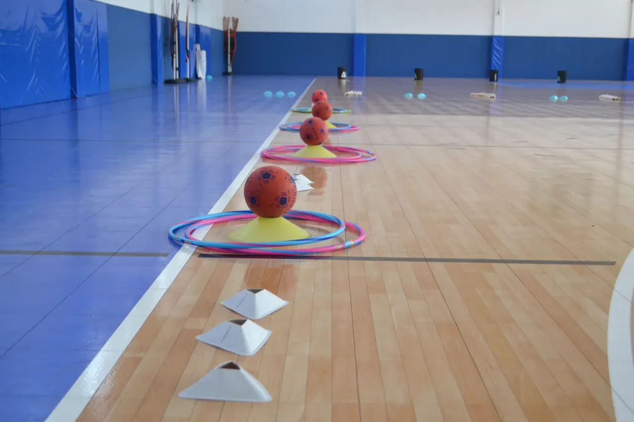 Vista de un reto en interiores con aros y pelotas, diseñado para fomentar la creatividad y la cooperación entre maestros