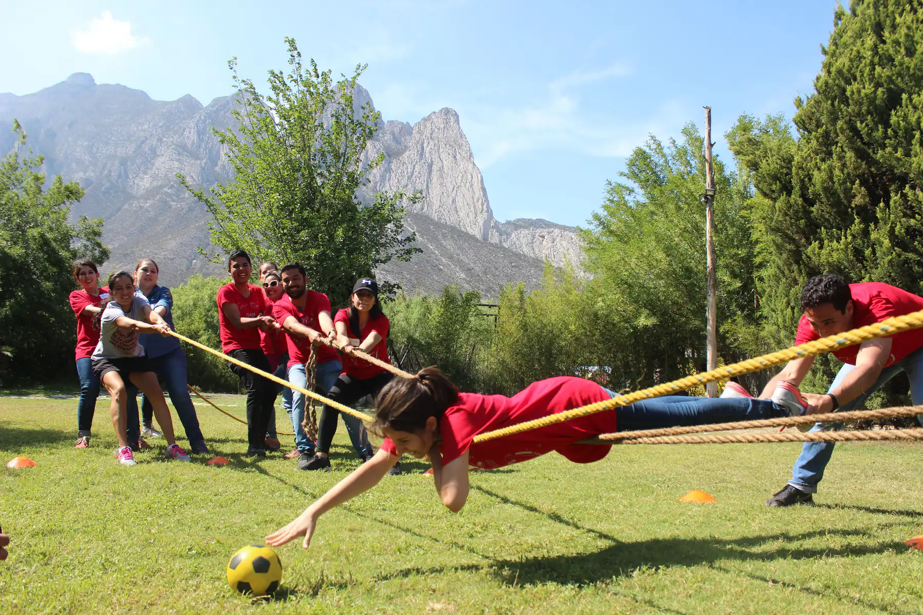 Equipo de una empresa jalando la cuerda en una dinámica de team building de ALYAX al aire libre, con la Sierra Madre de Monterrey al fondo